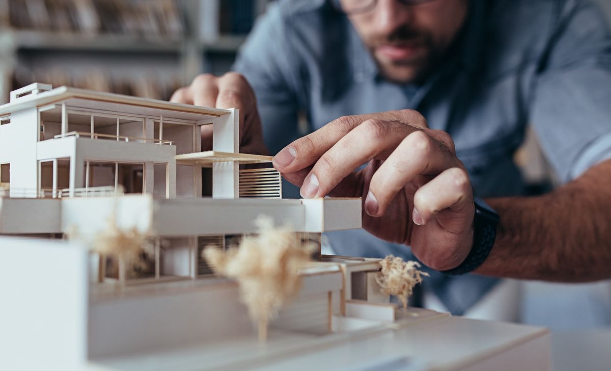 Architecte en train de travailler sur des plans dans son bureau, avec une calculatrice et des documents de rémunération